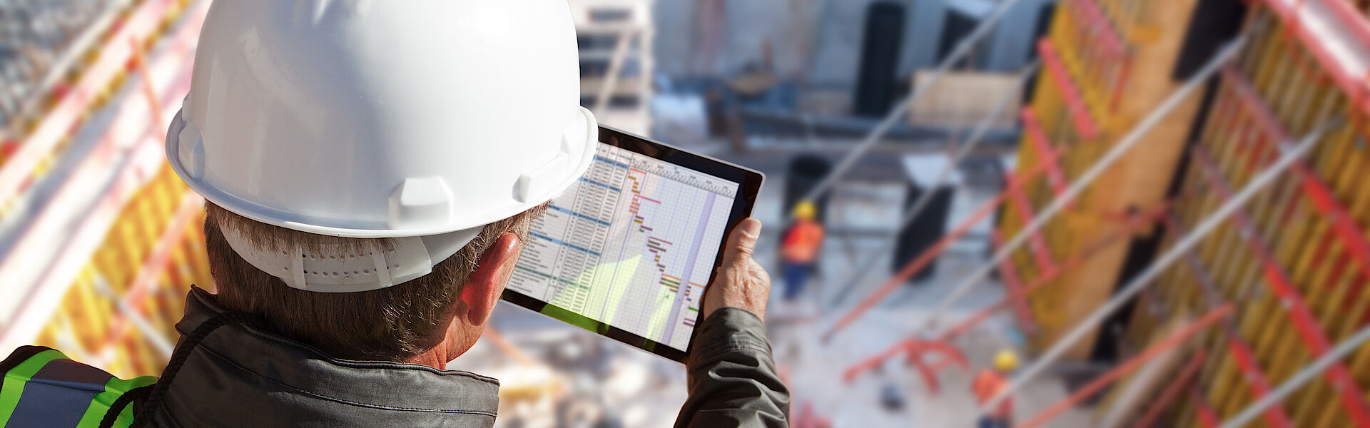 Worker at a building site looking at data on a mobile device | DMT GROUP